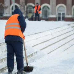 Une personne déblaye la neige d’une surface pavée.