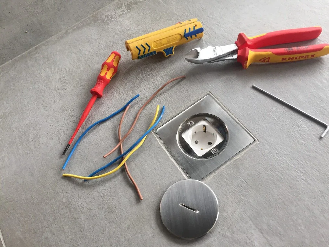 Electrician’s tools beside a floor socket being fitted
