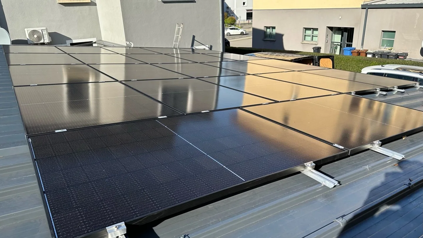 Rows of black solar panels on a company roof