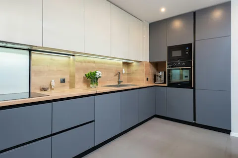Modern fitted kitchen with dark lower cabinets, light upper cabinets and integrated appliances.
