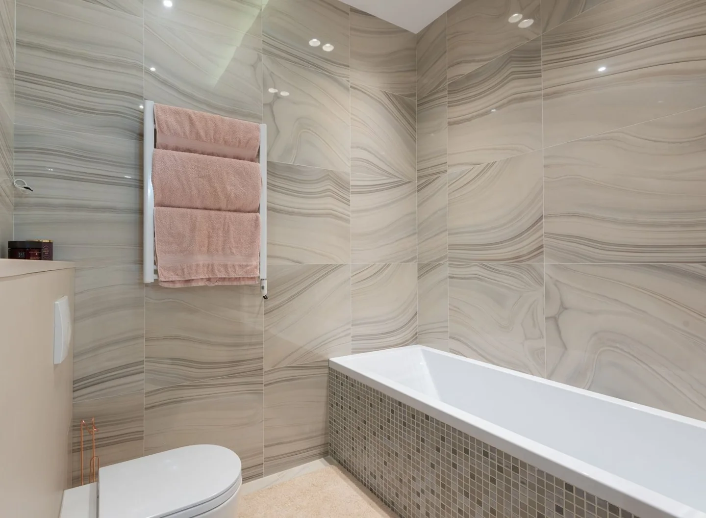 Saniertes Bad mit grauen Fliesen in Steinoptik, Holzwaschtisch und Wanne (Symbolfoto)