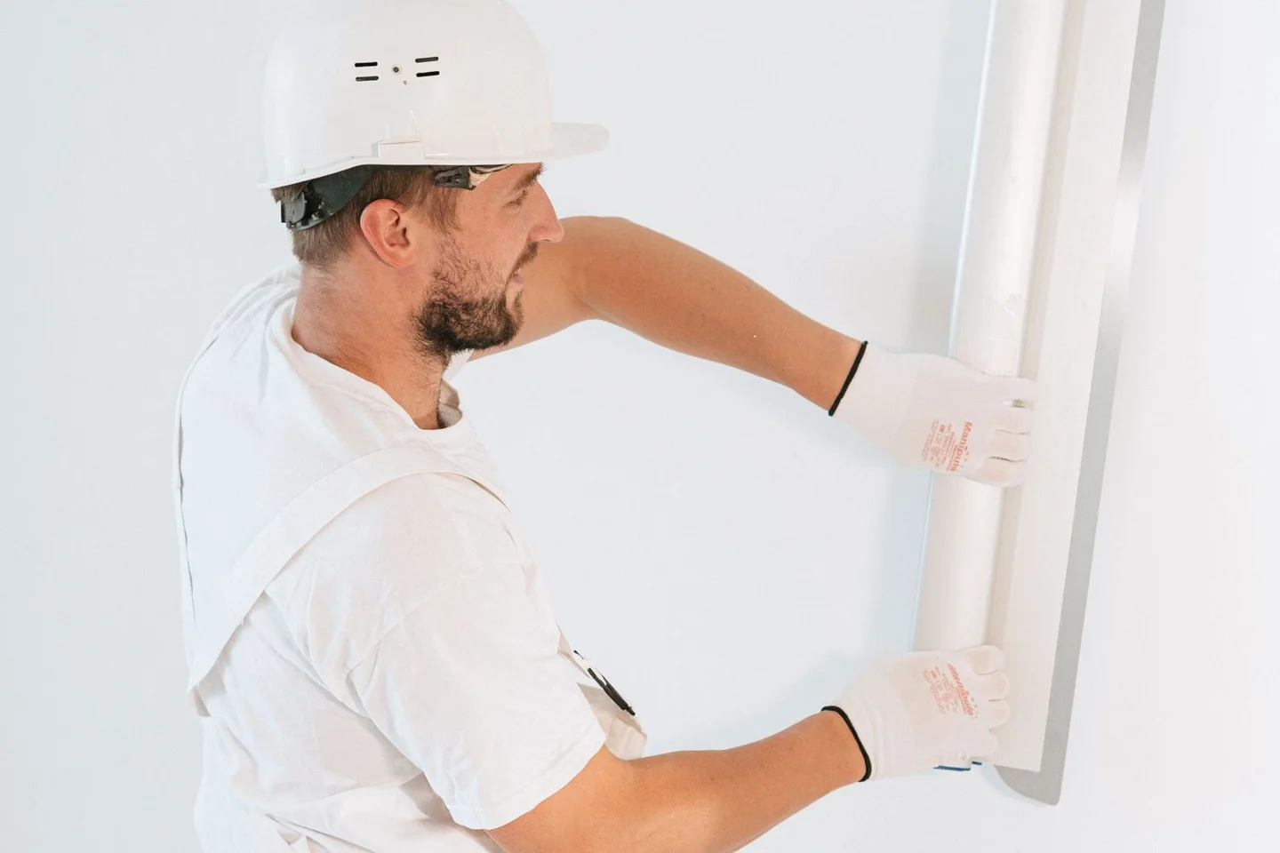Fitter positioning a plasterboard panel (stock photo)