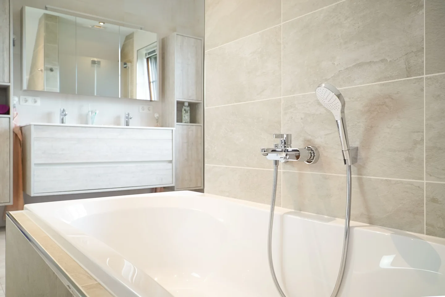 Built-in bathtub with a hand shower and wall-mounted fittings