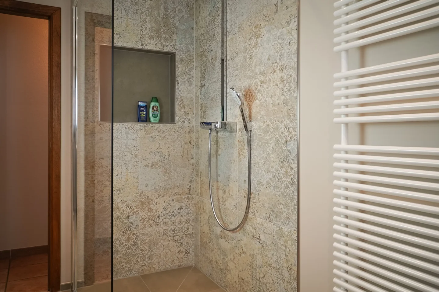 Walk-in shower with a tiled niche and rain shower