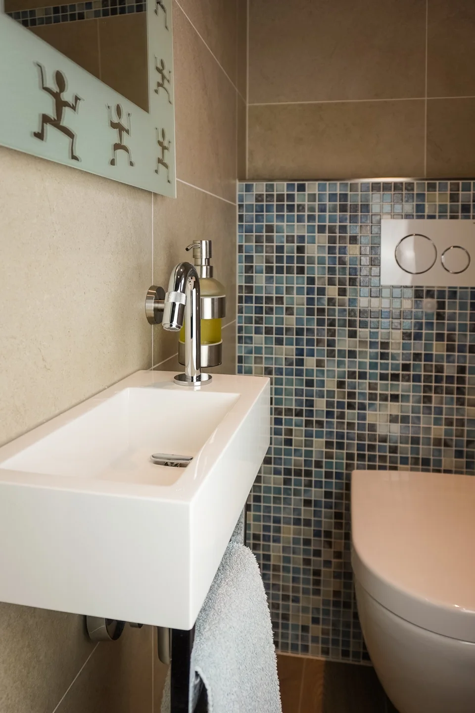 Guest toilet with a mosaic wall and compact basin