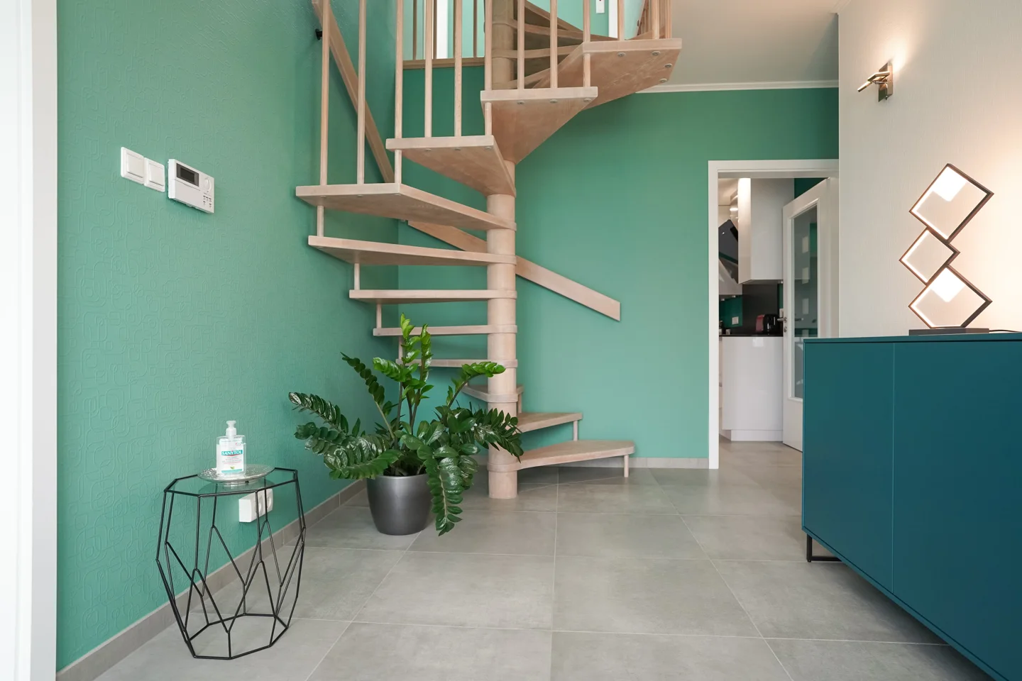 Tiled entrance hall and living room with a green wall and open staircase