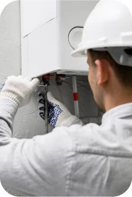 Technician working on a wall-mounted heating unit.