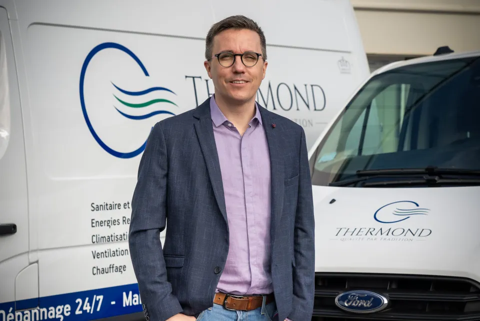 Person standing beside a branded service van.