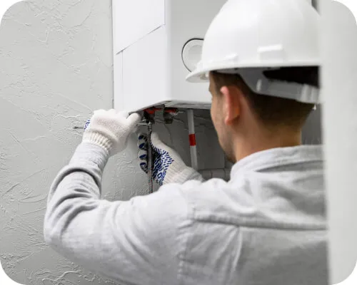 Technician working on a wall-mounted heating unit.