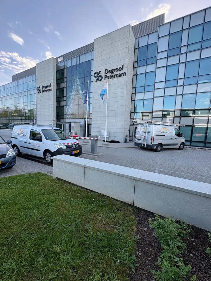 Véhicules marqués garés devant un immeuble de bureaux.