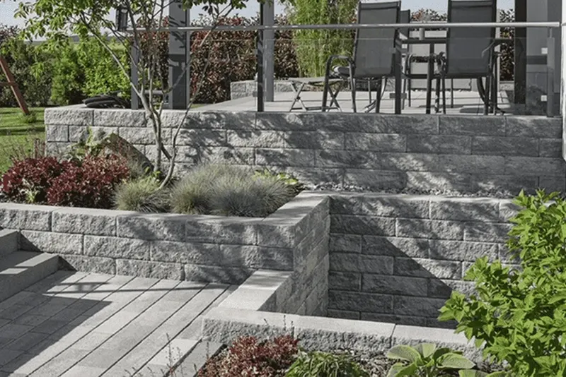 Terraced garden with stone retaining walls, paving and planted beds.