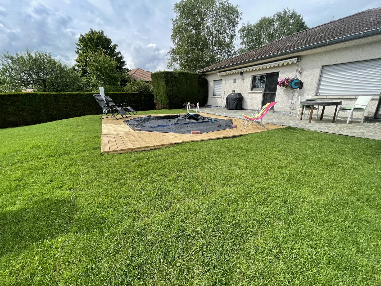 Lawn and round wooden deck around a garden pool