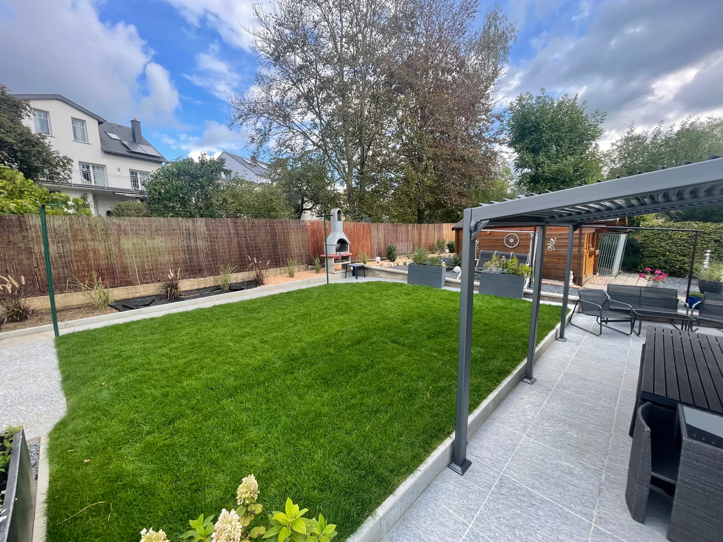 New lawn, pergola and terrace behind a house