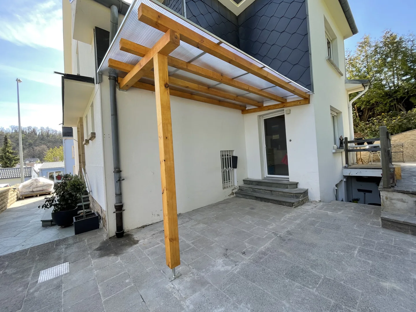 Paved terrace and wooden pergola against the house