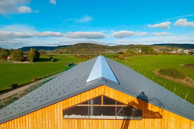 Finished grey metal roof on a building in a rural setting.