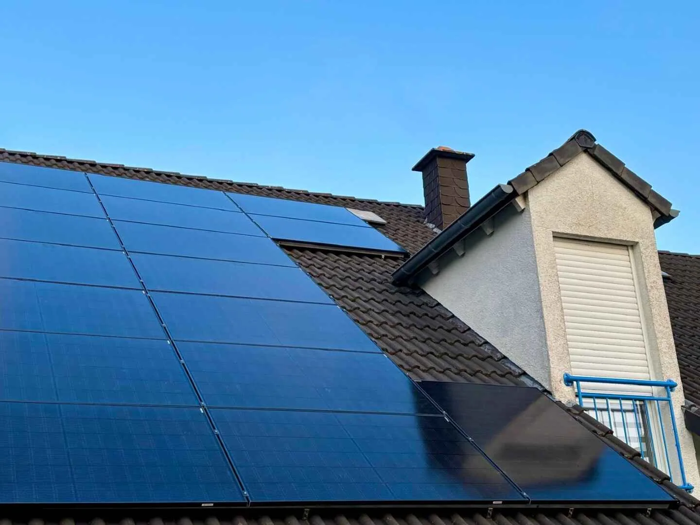 Full Black photovoltaic panels on a pitched roof beside a dormer