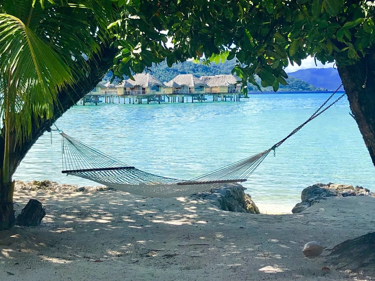Hängematte unter Bäumen mit Blick auf Überwasser-Bungalows