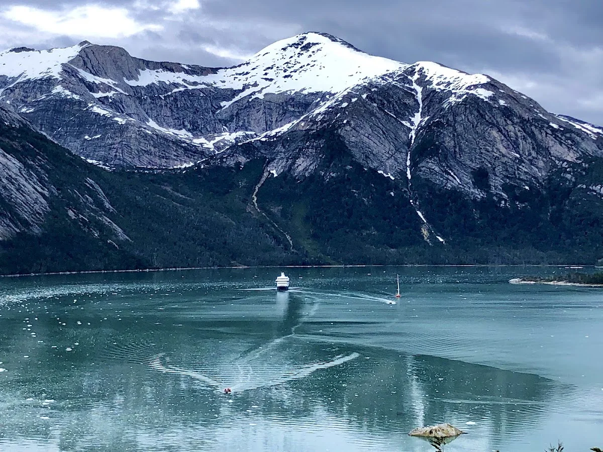 Expeditionsschiff in einem Fjord unter schneebedeckten Gipfeln
