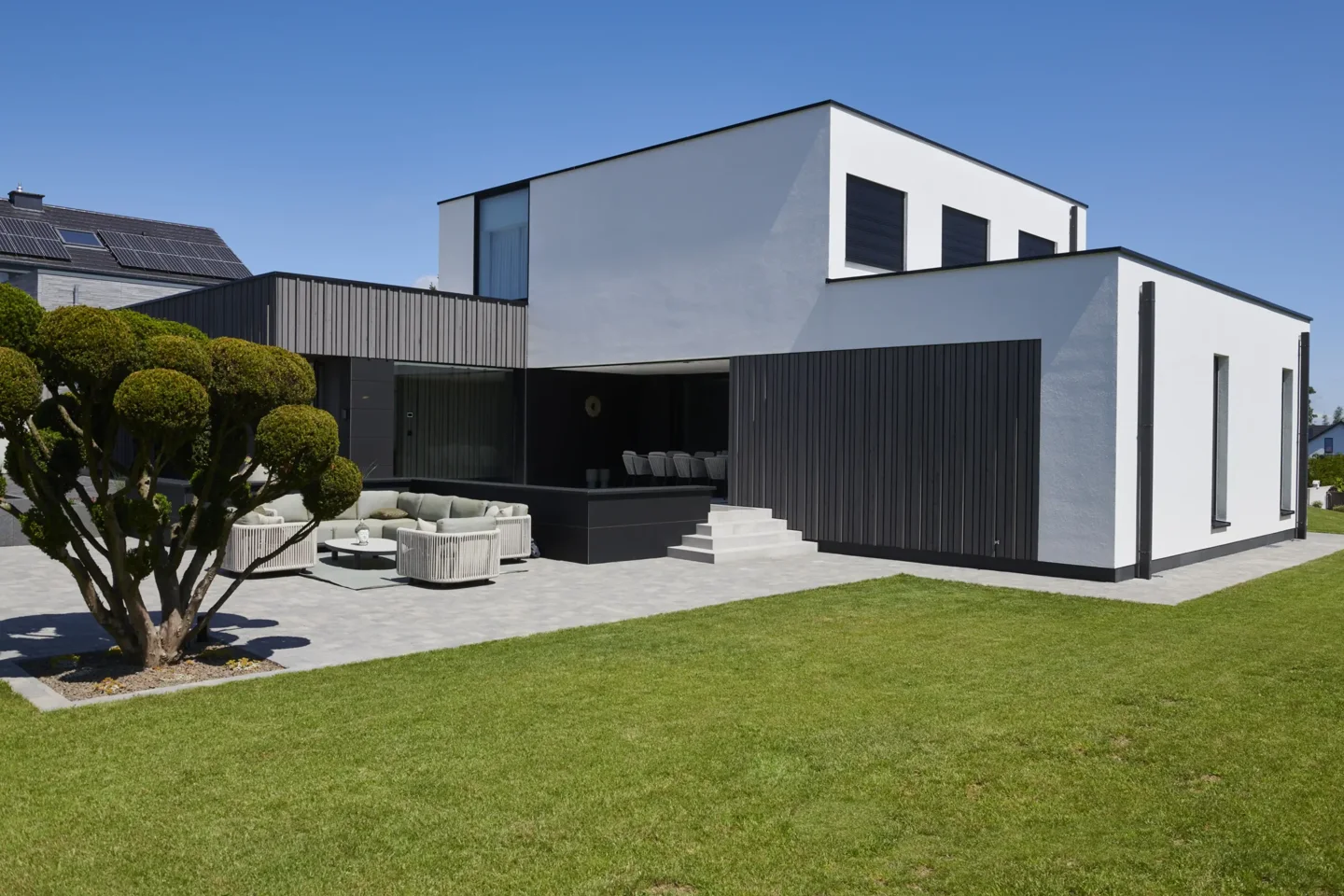 Modernes Haus mit dunklem Putz und gepflasterter Terrasse