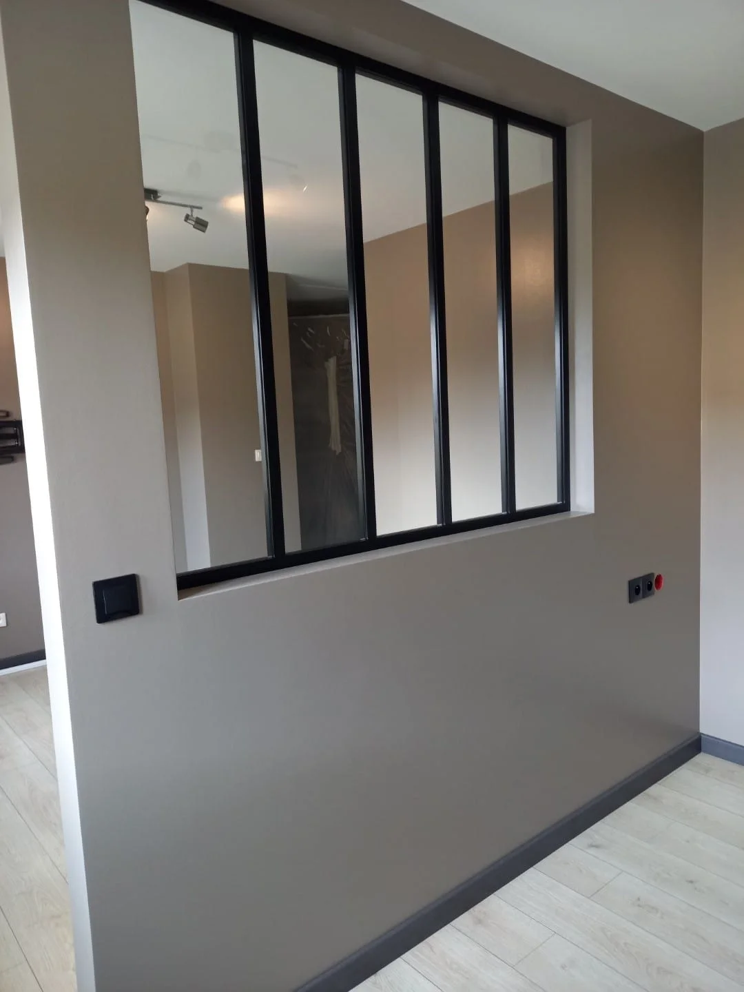Partition with a black-framed glazed panel in a freshly painted room