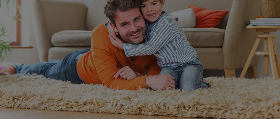 Erwachsener und Kind liegen gemeinsam auf einem Teppich.