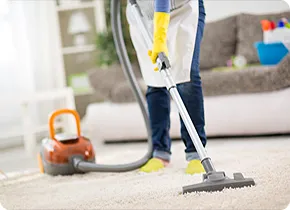 Person saugt einen Teppich in einem Wohnzimmer.