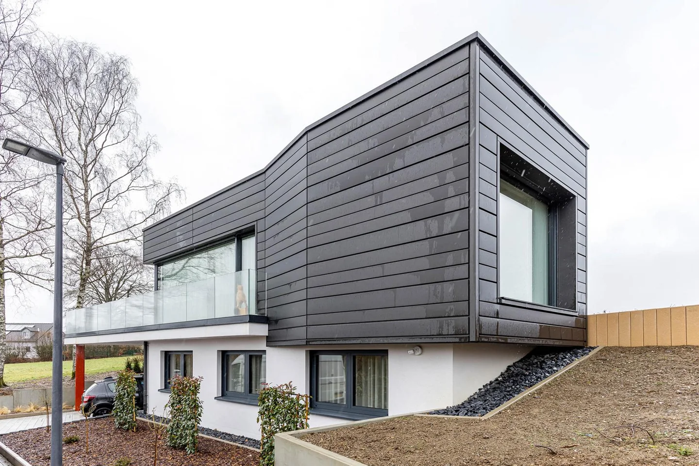 Turnkey timber house in Asselborn with dark cladding and glazed corner