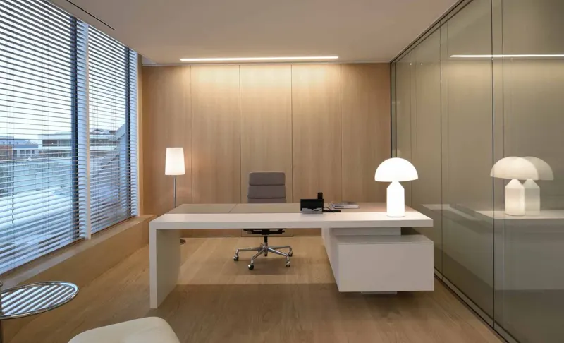 Furnished office with a built-in wall, glass partition and venetian blinds.