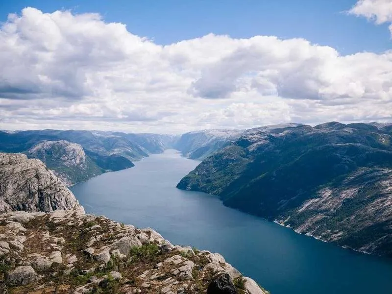 Mountain landscape with a fjord under a cloudy sky.
