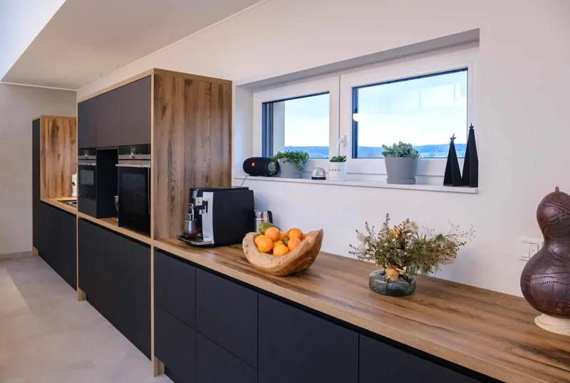 Kitchen with dark cabinetry, wood worktop and a window.